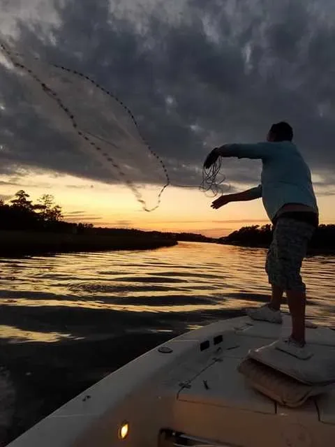 Angler throwing a cast net at dusk