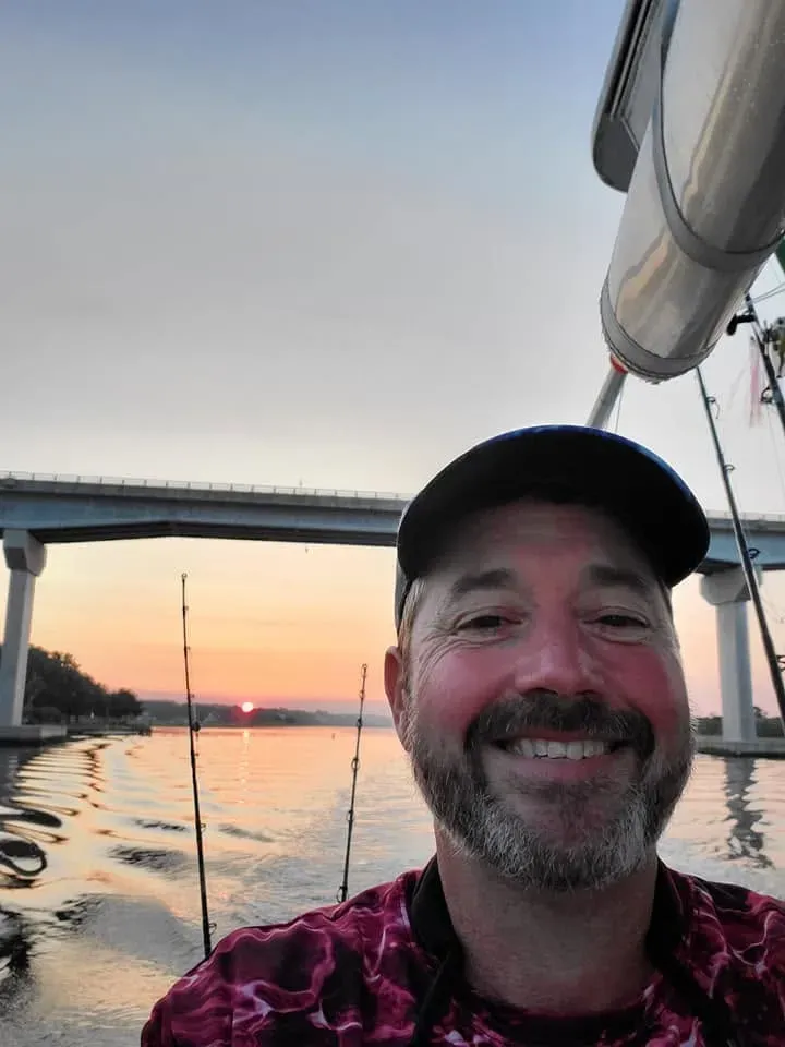 Marty Gribble smiling on his boat at sunset